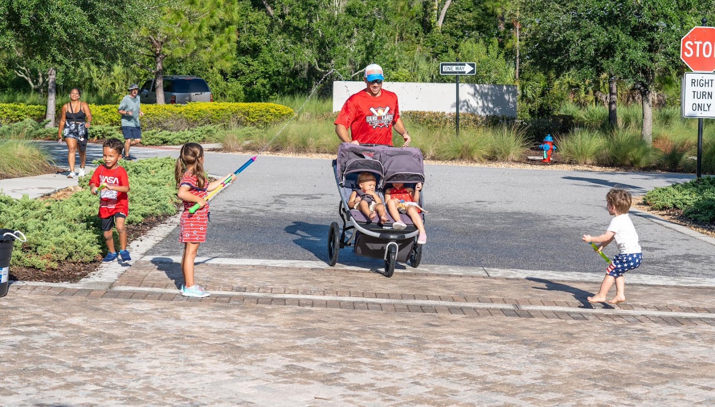 Kids playing with water guns as a stroller dad finishes a race
